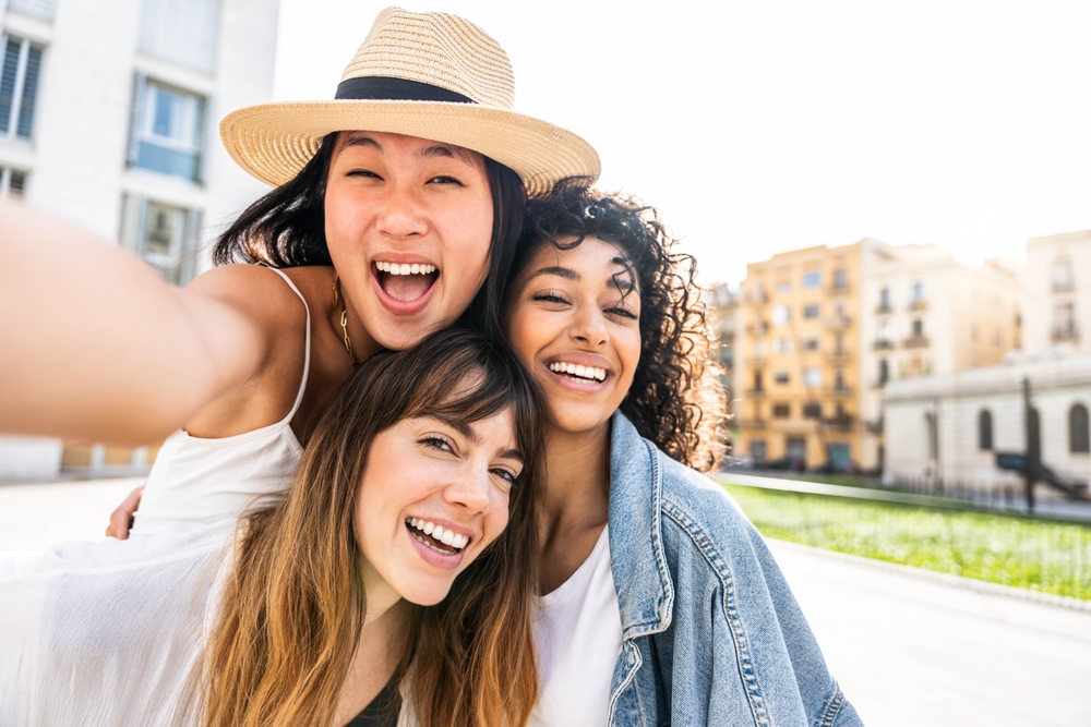 Three smiling women taking a selfie outdoors