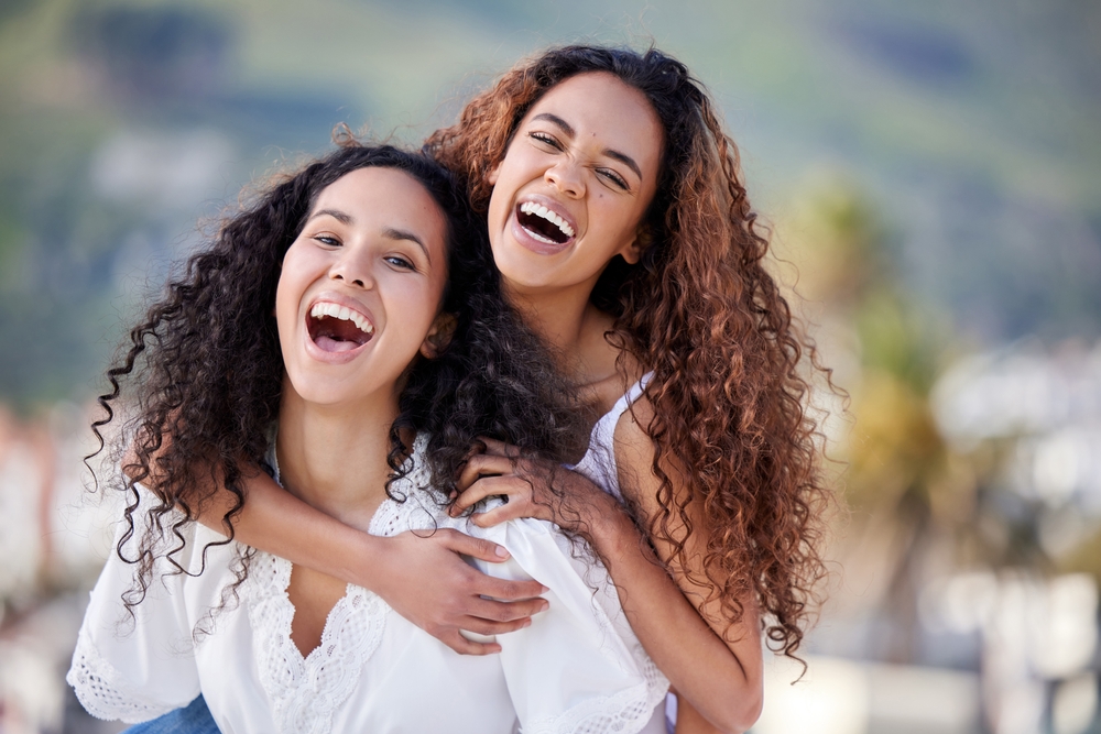 Two women laughing and embracing outdoors