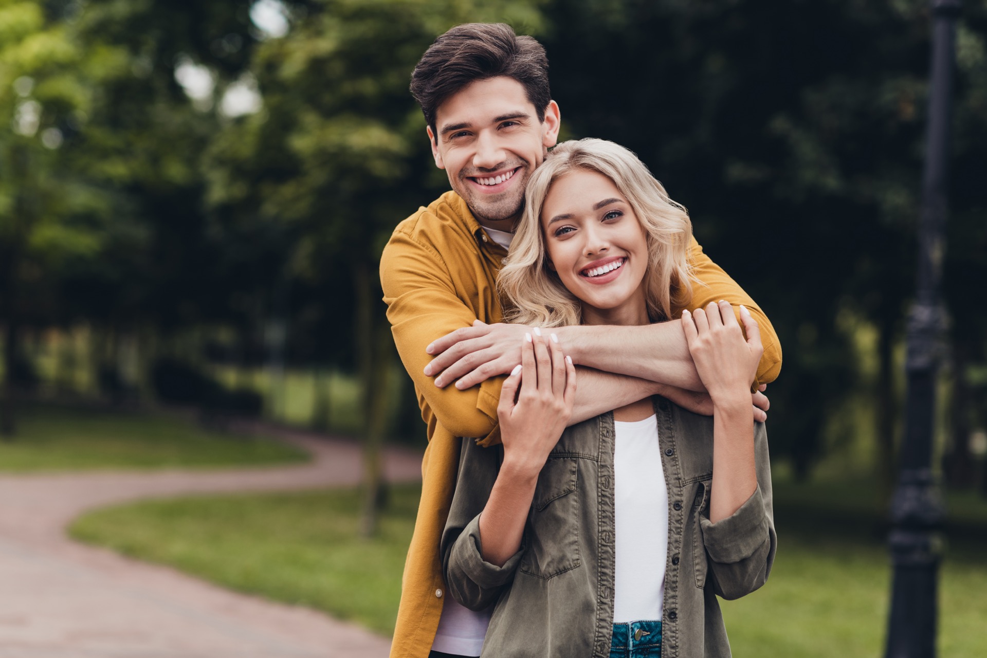 A smiling couple embracing in a green park