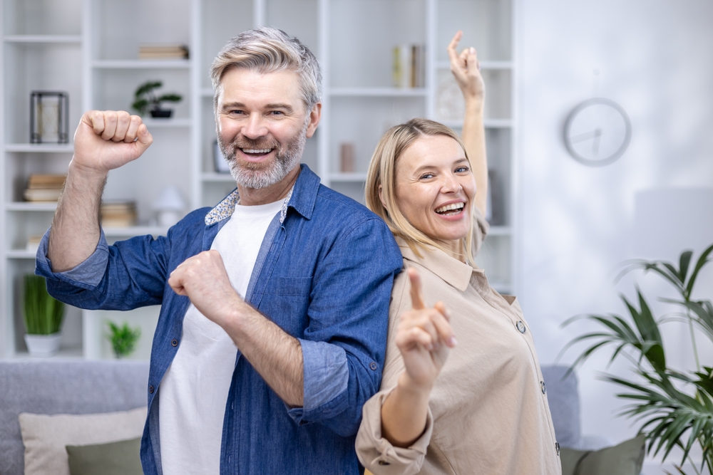 A smiling couple dancing together at home