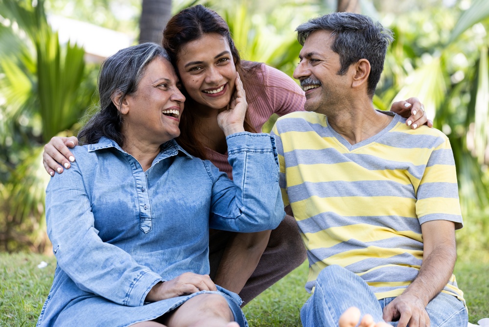 A smiling young woman embracing an older couple outdoors
