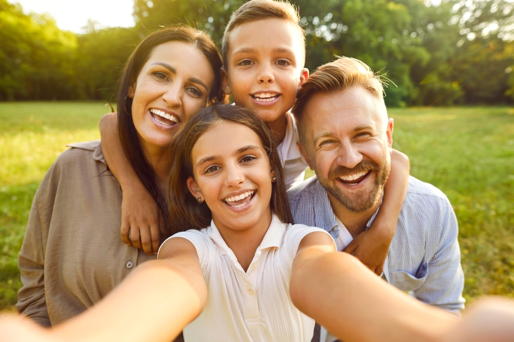 Smiling parents and their two children taking a selfie outdoors